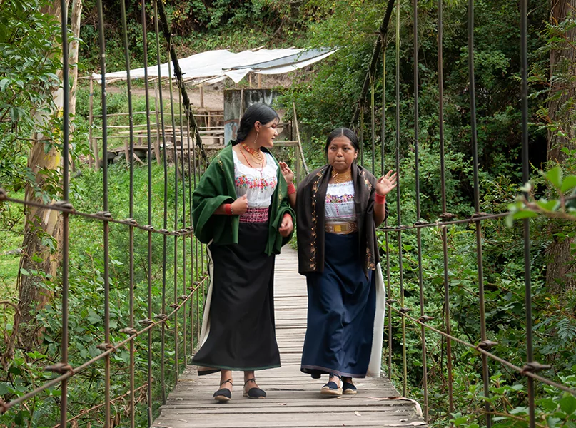 indigenous friends crossing over a suspension bridge