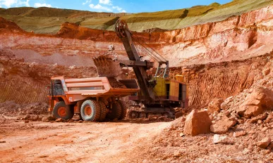 Aluminium ore mining and transporting. Excavator loads bauxite clay to Hitachi quarry dump truck.