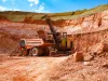 Aluminium ore mining and transporting. Excavator loads bauxite clay to Hitachi quarry dump truck.